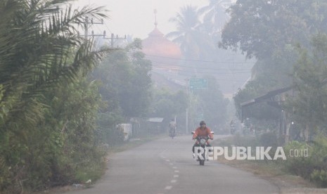 Pengendara sepeda motor melaju menembus kabut asap akibat Kebakaran Hutan dan Lahan (Karhutla) saat melintasi jalan Desa Pinem, Kecamatan Samatiga, Aceh Barat, Aceh, Selasa (6/8/2019).