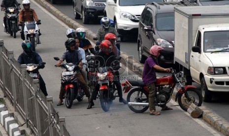 Pengendara sepeda motor melewati separator keluar dari jalur busway di jalan Warung Buncit, Jakarta Selatan, Ahad (11/11).  