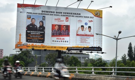 Pengendara sepeda motor melintas di dekat baliho sosialisasi Pilkada Gubernur dan Wakil Gubernur DKI Jakarta Tahun 2017 di Jakarta, Jumat (10/2).