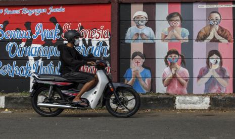 Pengendara sepeda motor melintas di dekat mural bergambar simbol orang berdoa menggunakan masker yang mewakili umat beragama di Indonesia di kawasan Juanda, Kota Depok, Jawa Barat, Kamis (18/6/2020). Mural yang dibuat oleh warga itu bertujuan untuk memberikan edukasi kepada masyarakat untuk menggunakan masker sebagai salah satu pencegahan dan penyebaran COVID-19.