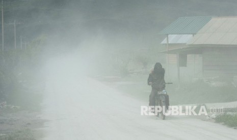 Pengendara sepeda motor melintas di jalan yang dipenuhi debu vulkanik erupsi Gunung Sinabung, di Desa Naman Teran, Karo, Sumatera Utara, Kamis (28/12). 