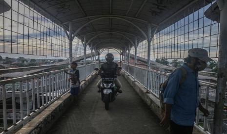 Pengendara sepeda motor melintas di Jembatan Penyeberangan Orang (JPO) di Cilebut, Kabupaten Bogor, Jawa Barat, Senin (14/2/2022). JPO yang seharusnya hanya untuk pejalan kaki tersebut dipergunakan juga oleh pengendara sepeda motor menyeberang sehingga mengganggu dan berpotensi membahayakan pejalan kaki.