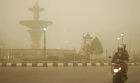 Pengendara sepeda motor melintas di kawasan Bundaran Air Mancur yang tertutup kabut asap tebal di Muara Teweh, Kabupaten Barito Utara, Kalimantan Tengah, Kamis (22/10).