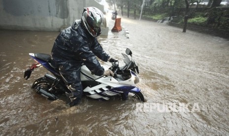 Pengendara sepeda motor melintasi banjir yang menggenangi kawasan Semanggi di Jakarta, Senin (11/12).