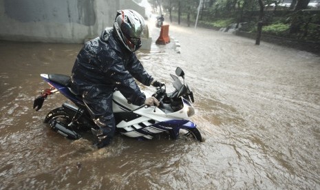 Pengendara sepeda motor melintasi banjir yang menggenangi kawasan Semanggi di Jakarta, Senin (11/12). Hujan deras disertai angin menyebabkan beberapa ruas jalan tergenang air.