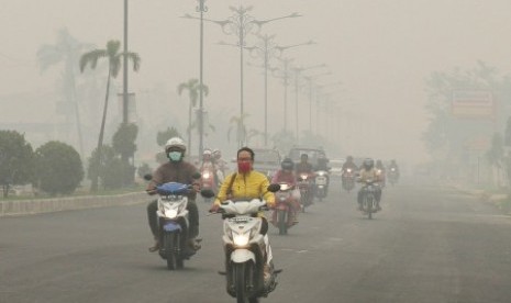 Pengendara sepeda motor melintasi jalan ketika kabut asap pekat menyelimuti Kota Pekanbaru, Riau. ilustrasi