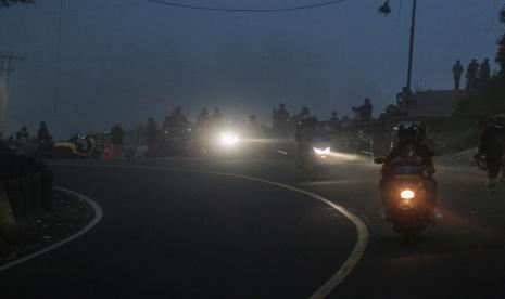 Pengendara sepeda motor melintasi jalan saat mendung hitam akibat cuaca ekstrem (ilustrasi).