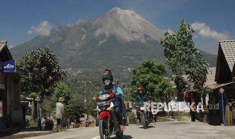 Pengendara sepeda motor memakai masker saat melintas di jalan raya yang tertutup abu vulkanis Gunung Merapi di Wonolelo, Sawangan, Magelang, Jawa Tengah, Jumat (1/6). 