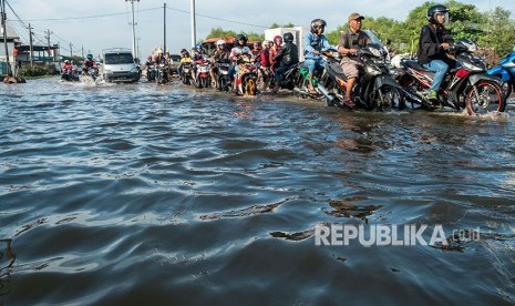 Pengendara sepeda motor menembus jalan yang terendam sisa rob akibat runtuhnya tembok tepi penahan (parapet) Sungai Sringin pada Rabu (23/5) karena tak mampu menahan debit pasang air laut setinggi 1,7 meter di Kawasan Industri Terboyo, Semarang, Jawa Tengah, Jumat (25/5). 