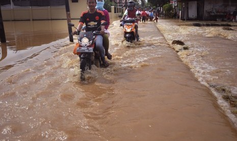 Pengendara sepeda motor menerobos genangan air 