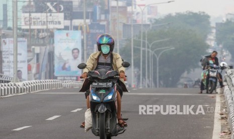 Pengendara sepeda motor menggunakan masker pelindung pernapasan ketika kabut asap karhutla menyelimuti Kota Pekanbaru, Riau, Selasa (30/07/2019). 