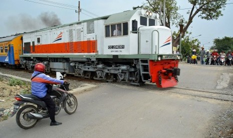 Pengendara sepeda motor menghentikan kendaraannya saat sebuah kereta api melintas di perlintasan kereta api tanpa palang pintu di Kelurahan Kemijen Semarang, Jawa Tengah, Kamis (9/7).