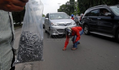   Pengendara sepeda motor secara sukarela membersihkan ranjau paku yang bertebaran di jalan Veteran, Jakarta Pusat, Rabu (20/2).  (Republika/Agung Fatma Putra)