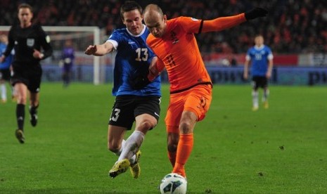 Penggawa timnas Estonia, Martin Vunk berebut bola dengan Arjen Robben.