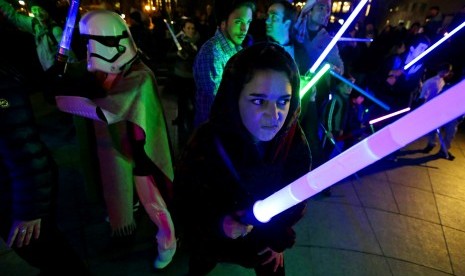 Penggemar film Star Wars bermain dengan senjata lightsaber khas dari film tersebut.