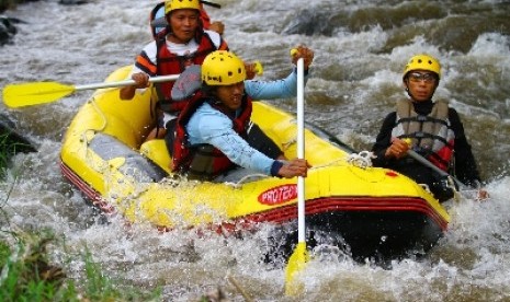 Penggemar olahraga arung jeram melintasi arus deras di hulu Sungai Brantas di Kota Batu, Sabtu (10/3).