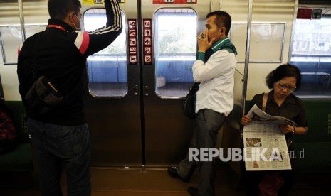 Pengguna Commuter Line membaca koran saat menaiki kereta, Jakarta, Kamis (4/2). 