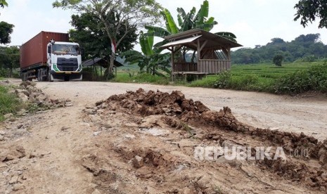 Pengguna jalan dan kontainer melintasi jalan lingkar barat KM 0 yang kondisinya rusak parah, di Kampung Cikadu, Desa Kadu Mekar, Kecamatan Babakan Cikao, Purwakarta, Rabu (14/3). 