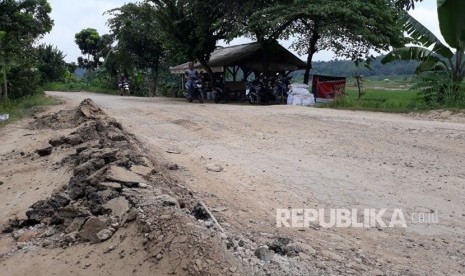 Pengguna jalan dan kontainer melintasi jalan lingkar barat KM 0 yang kondisinya rusak parah, di Kampung Cikadu, Desa Kadu Mekar, Kecamatan Babakan Cikao, Purwakarta, Rabu (14/3). 