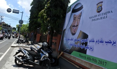 Pengguna jalan melintas di dekat baliho bergambar Raja Arab Saudi Salman bin Abdulaziz al Saud di kantor Polda Bali.