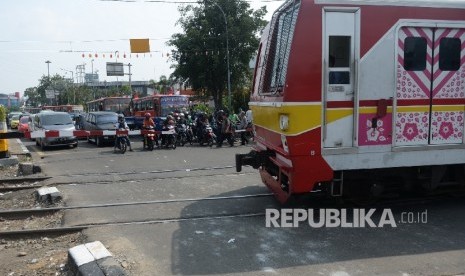 Pengguna jalan menunggu di perlintasan kereta api (Republika/ Wihdan)