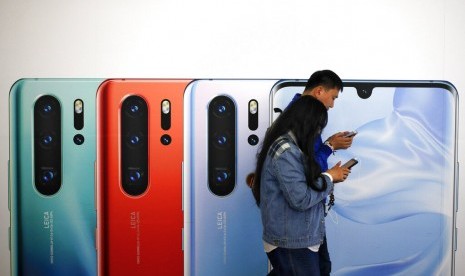 Pengguna ponsel melewati iklan Huawei p30 di Beijing, China.