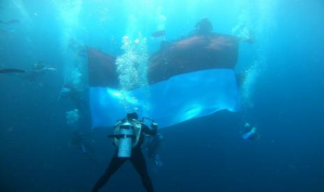 Pengibaran bendera merah putih di bawah laut salah satu pulau terluar Indonesia, Pulau Maratua, Kalimantan Timur.