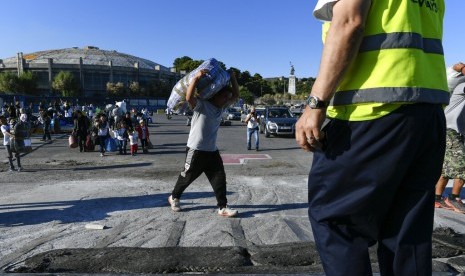 Pengungsi dan migran membawa barang bawaan mereka untuk berlayar dengan feri ke pelabuhan Piraeus di timur laut Lesbos, Yunani. Yunani kembali tutup kamp pengungsi setelah ada pengungsi yang positif corona. Ilustrasi.