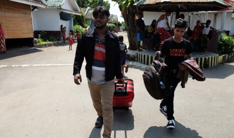 Pengungsi etnis Rohingya, Myanmar Hasan Ali (kanan) dibantu rekannya sesama pengungsi membawa barang-barangnya saat akan berangkat ke bandara untuk diterbangkan ke Amerika Serikat di lokasi penampungan, Medan, Sumatera Utara, Rabu (19/6/2019). 