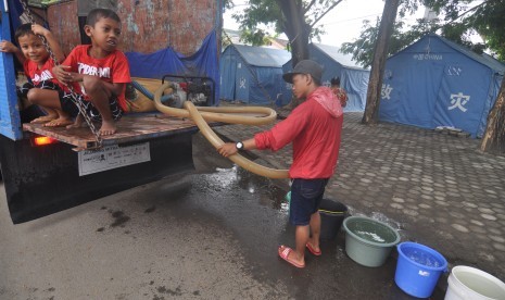 Pengungsi korban bencana gempa, tsunami dan likuifaksi mengambil air bersih yang disalurkan ke tenda hunian mereka di Kamp Pengungsian, Palu, Sulawesi Tengah, Kamis (17/1/2019).