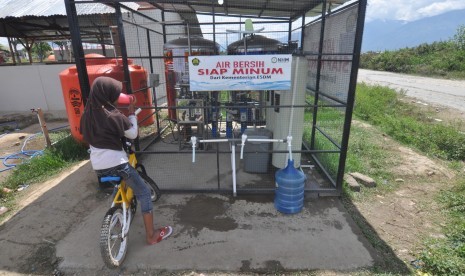 Pengungsi korban gempa dan likuifaksi mengisi air ke dalam galon dan meminum air siap minum yang disediakan secara gratis di Lokasi Pengungsian di Desa Lolu, Kabupaten Sigi, Sulawesi Tengah, Jumat (30/11/2018). 