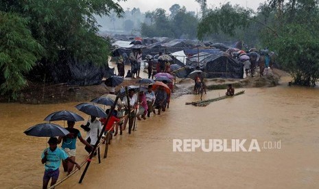 Pengungsi melintasi sungai yang meluap di kamp pengungsi Rohingya di Cox's Bazaar, Bangladesh, Selasa (19/9).