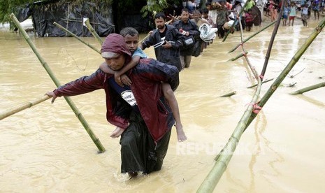 Pengungsi melintasi sungai yang meluap di kamp pengungsi Rohingya di Cox's Bazaar, Bangladesh, Selasa (19/9).