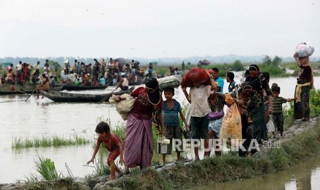 Pengungsi Rohingya berjalan di jalan berlumpur di pesawahan setelah melintasi perbatasan Bangladesh-Myanmar di Teknaf, Bangladesh, Rabu (6/9).