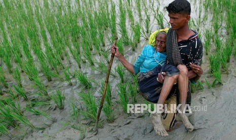 Pengungsi Rohingya dibopong melintasi pesawahan setelah melintasi perbatasan Bangladesh-Myanmar di Teknaf, Bangladesh, Rabu (6/9).