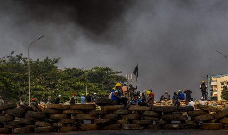 Pengunjuk rasa anti-kudeta mengambil posisi di Jembatan Bayint Naung, diblokir dengan barikade yang diimprovisasi untuk mencegah pasukan keamanan Myanmar menyeberang, ketika asap membubung dari ban yang terbakar di Yangon, Myanmar pada Rabu, 17 Maret 2021