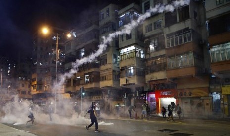 Pengunjuk rasa bereaksi terhadap gas air mata dari kantor polisi Shum Shui Po di Hong Kong, Rabu (14/8).