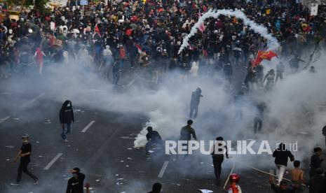 Pengunjuk rasa berlarian ketika polisi menembakkan gas air mata saat demo menolak Undang-undang Cipta Kerja di depan Gedung Negara Grahadi, Surabaya, Jawa Timur, Kamis (8/10/2020). Aksi yang dikuti ribuan orang dari berbagai elemen mahasiswa dan buruh tersebut berakhir ricuh dan mengakibatkan sejumlah fasilitas umum rusak.