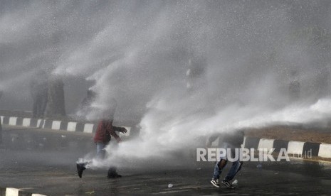 Pengunjuk rasa berusaha menghindari tembakan air mobil water canon saat aksi menuntut penuntasan kasus kematian mahasiswa di depan Polda Sulawesi Tenggara, Kendari, Sulawesi Tenggara, Selasa (22/10/2019). 