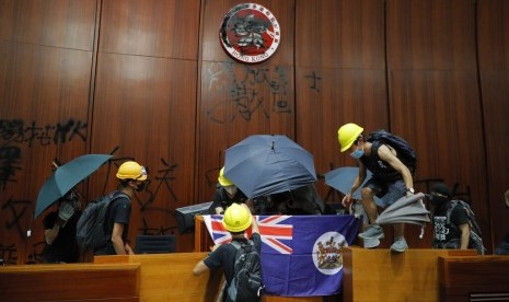 Pengunjuk rasa Hong Kong memasang bendera kolonial dan merusak logo Hong Kong di ruang utama gedung legislatif di Hong Kong, Senin (1/7).