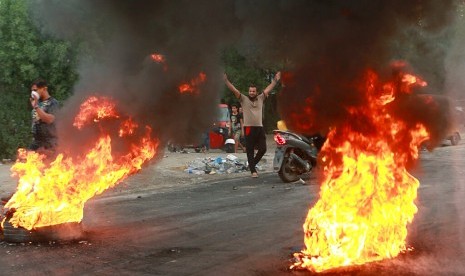 Pengunjuk rasa melakukan pembakaran dan memblokir jalan selama demonstrasi di Baghdad, Irak, Ahad (6/10). Lebih dari 100 orang meninggal dalam protes tersebut.