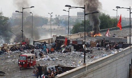 Pengunjuk rasa melakukan pembakaran dan membuat barikade di jembatan yang mengarah ke Zona Hijau saat demonstrasi di Baghdad, Irak, Ahad (27/10).