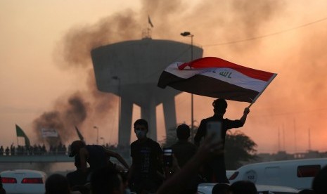 Pengunjuk rasa membawa bendera Irak dalam aksi protes di Baghdad, Irak, Rabu (2/10).