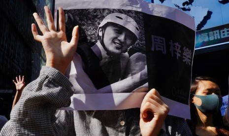 Pengunjuk rasa memegang foto demonstran Chow Tsz-Lok yang meninggal karena jatuh di Hong Kong, Jumat (8/11).