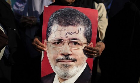  Pengunjuk rasa memegang foto Presiden Muhammad Mursi di Nasser City, Kairo, Mesir, Kamis (4/7).    (AP/Hassan Ammar)