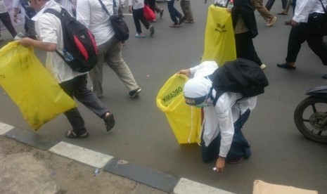 Pengunjuk rasa memunguti sampah di sepanjang jalan aksi dilakukan, Jumat (4/11). (Republika/Dadang Kurnia)