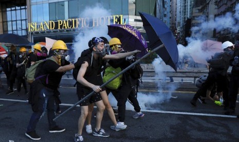 Pengunjuk rasa menggunakan payung untuk melindungi diri dari gas air mata di Hong Kong, Ahad (28/7).