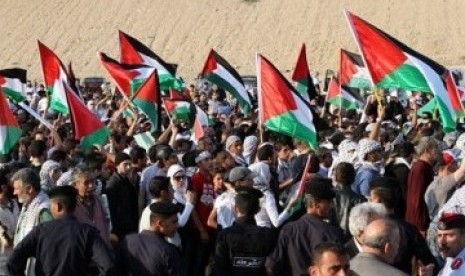 Pengunjuk rasa pro-Palestina di Yordania mengibarkan bendera ketika mendekati perbatasan Yordania-Israel, Ahad (15/5).