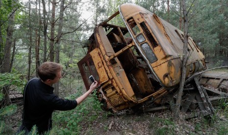 Pengunjung berfoto dekat bus yang ditinggalkan begitu saja setelah insiden nuklir Chernobyl di Rusia.