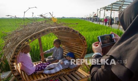 Pengunjung berfoto dengan latar belakang lahan persawahan di destinasi wisata Tegalan 21, Kampung Karang Tengah, Plawad, Karawang, Jawa Barat, Sabtu (28/8/2021). Destinasi wisata hasil swadaya masyarakat dan Karang Taruna tersebut menyajikan pemandangan lahan persawahan yang sekaligus menjadi tempat promosi dan dan penjualan produk UMKM sebagai upaya pengembangan desa wisata. 